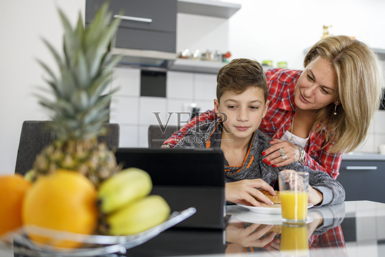 快乐的母亲和儿子看着数字平板电脑照片摄影图片