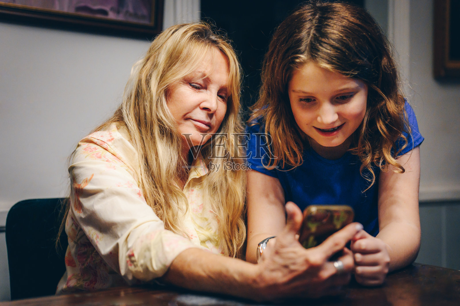 60多岁的女人在家里用手机，很开心照片摄影图片