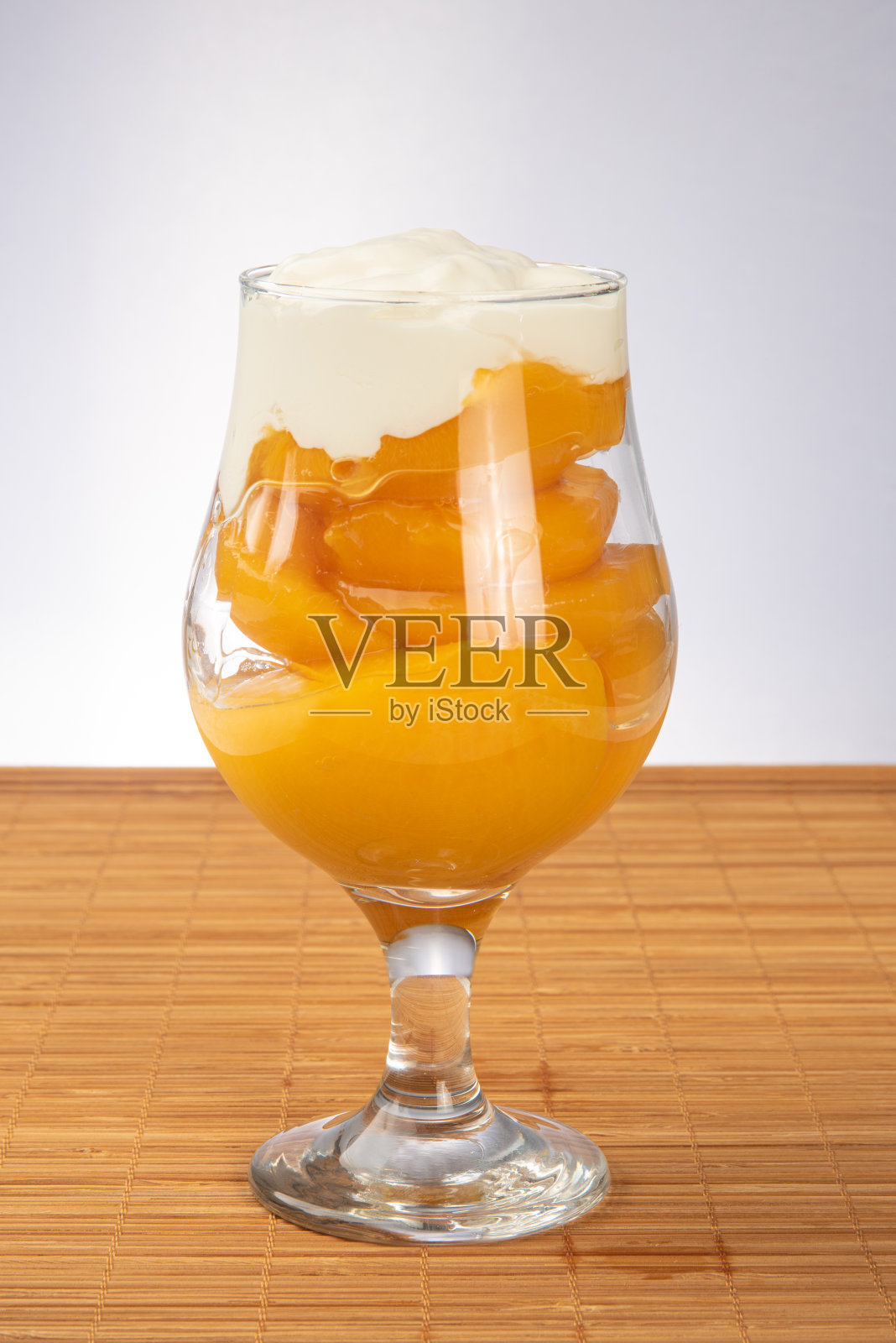 蜜桃放在碗里盖上酸奶油的木席上，背景呈灰色渐变，选择性聚焦。照片摄影图片