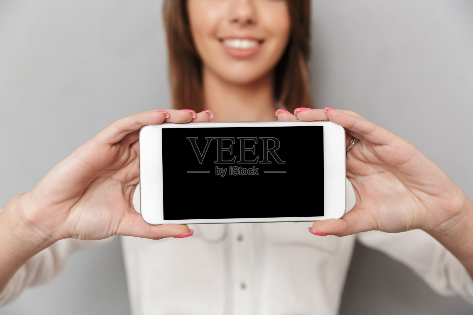 裁剪图像的愉快的年轻商业妇女展示手机。照片摄影图片