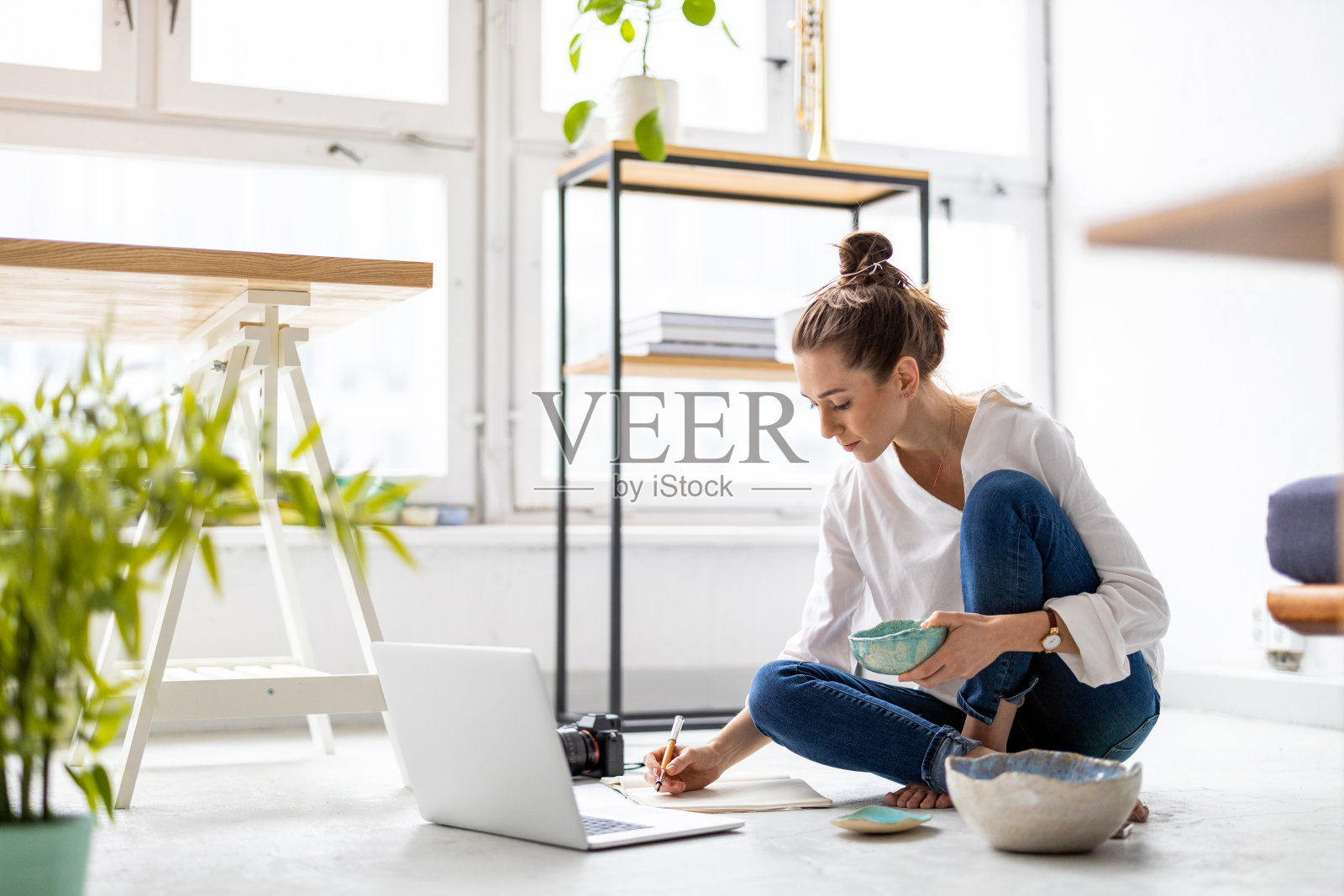 在她的工作室里用笔记本电脑工作的富有创造力的年轻女子照片摄影图片