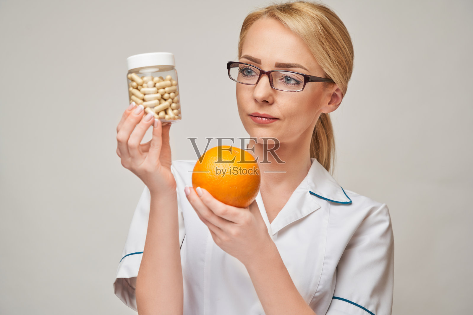 营养学家医生健康生活方式概念-持有橘子水果和营养维生素胶囊或药丸照片摄影图片