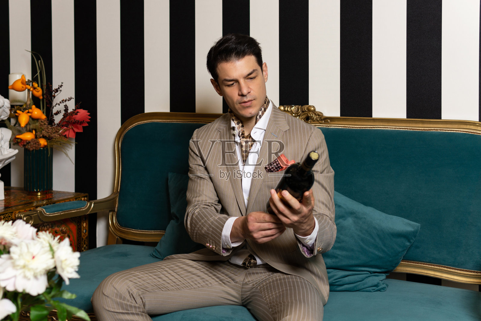 穿着西装拿着酒瓶的迷人男人。照片摄影图片