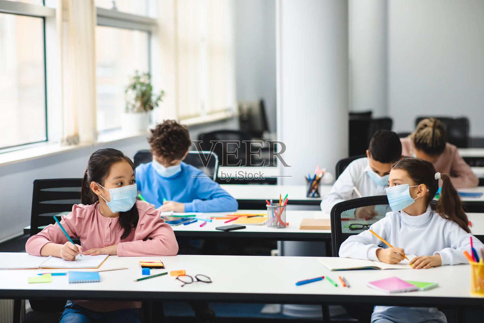 不同的学生戴着口罩在学校保持社交距离照片摄影图片