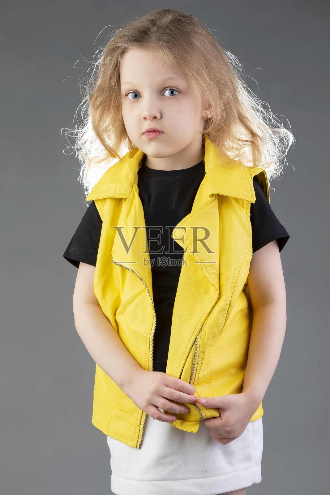 漂亮的金发小女孩，穿着黄色夹克，灰色背景。五岁的女孩。给孩子做模型测试。照片摄影图片