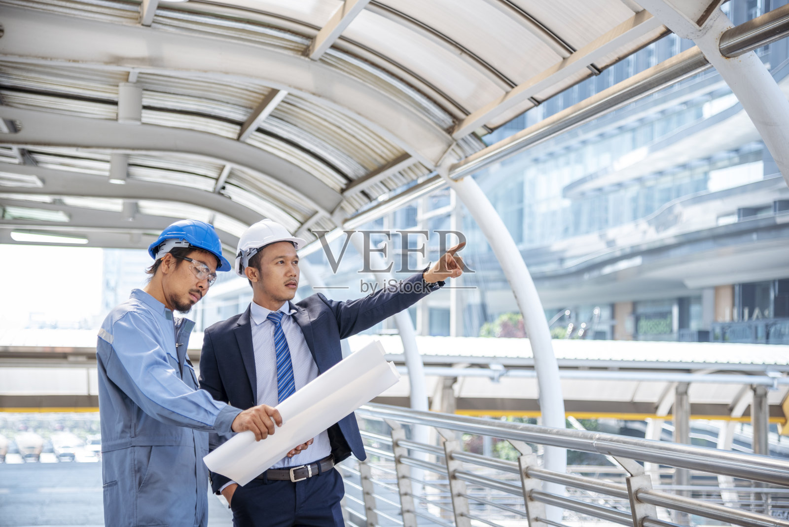 安全服信托团队的建筑工程师在施工现场手持黄白安全安全帽安全设备。土木建筑工程师安全帽保护头。工程概念照片摄影图片