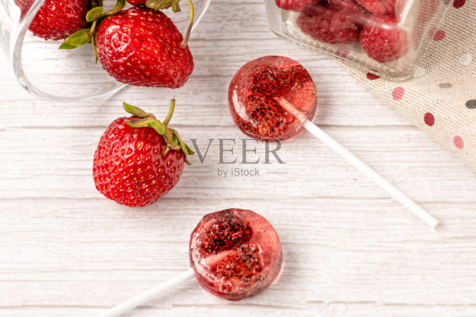 用天然脱水草莓和覆盆子制作的自制棒棒糖，放在白色的木质背景上。健康的素食，不含糖。照片摄影图片
