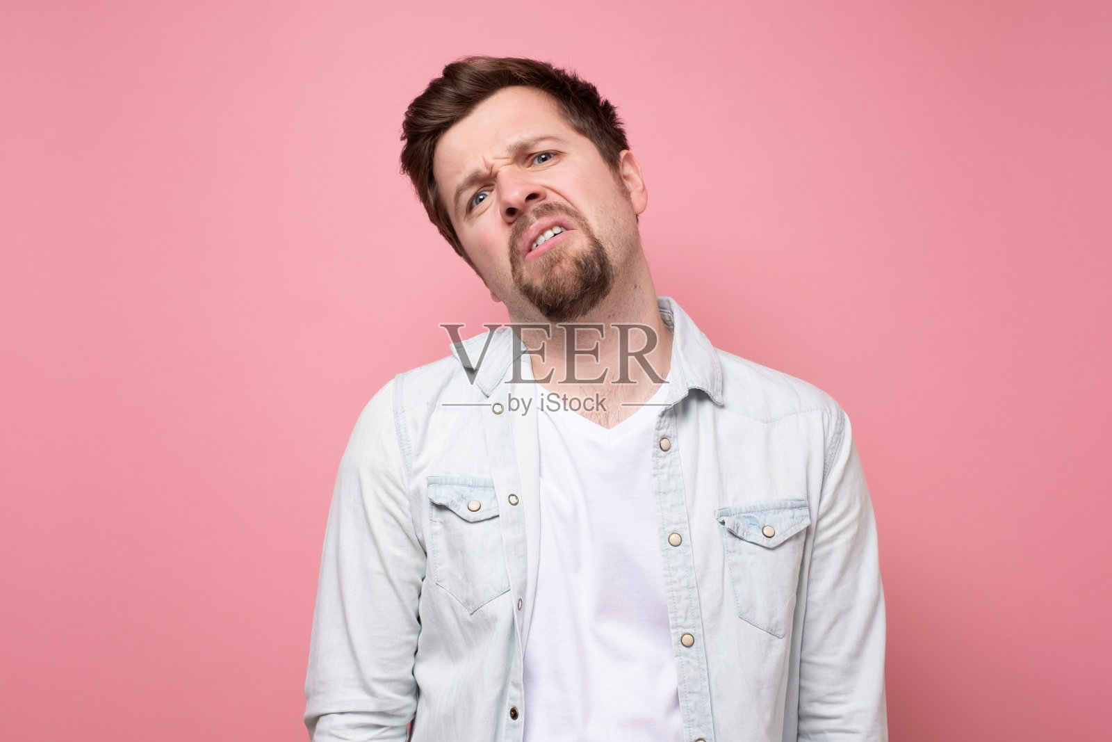 长着胡子的英俊男子正无聊地看着摄像机。照片摄影图片