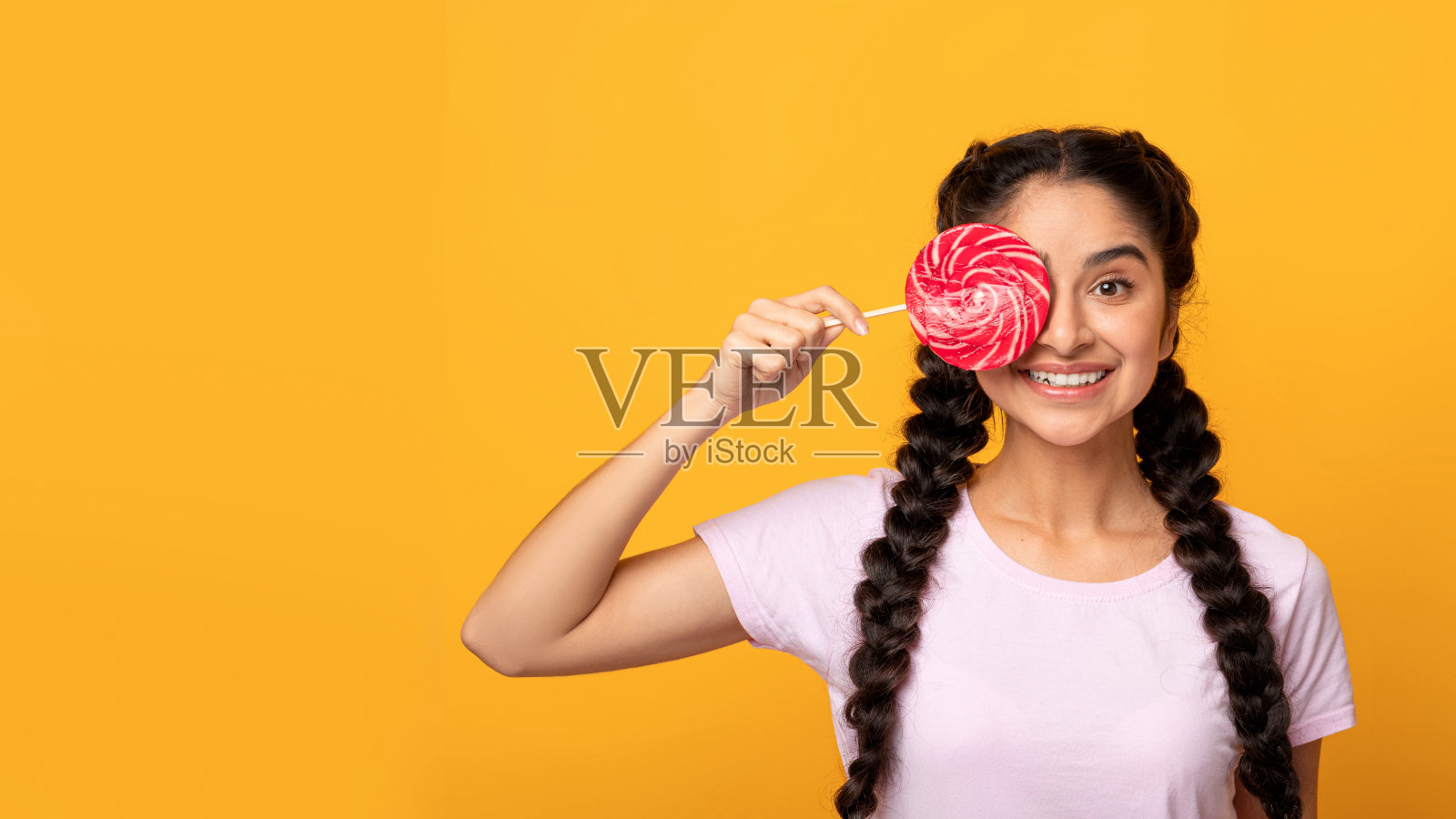印度女子拿着棒棒糖，用糖果遮住眼睛照片摄影图片