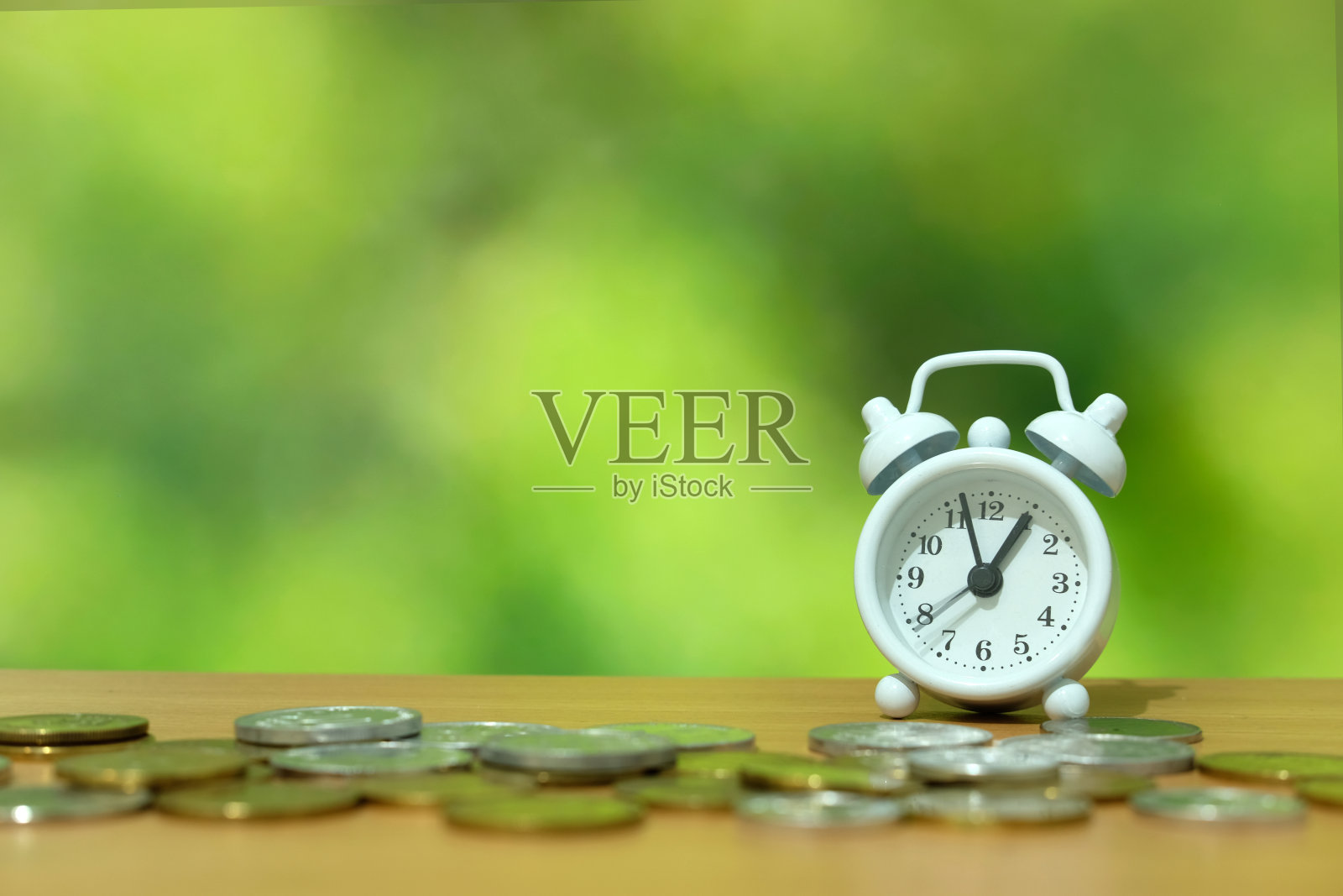 时间就是金钱的概念——一堆钱和一个木桌上的白色时钟。照片摄影图片