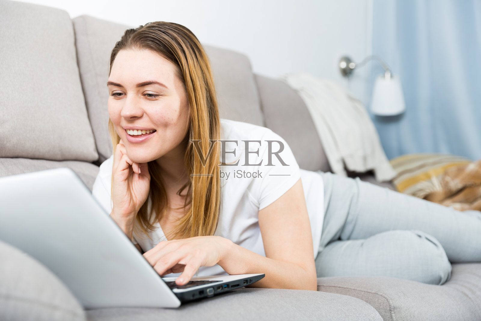 一个愉快的女性在沙发上用笔记本电脑工作的肖像照片摄影图片