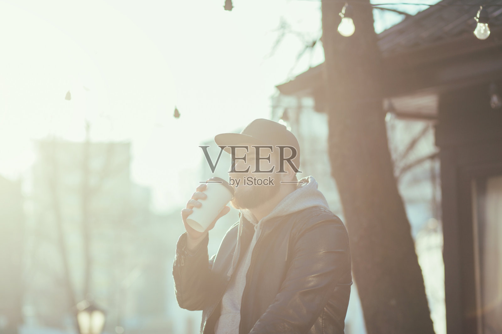 一个拿着咖啡杯在城市里走的男人照片摄影图片