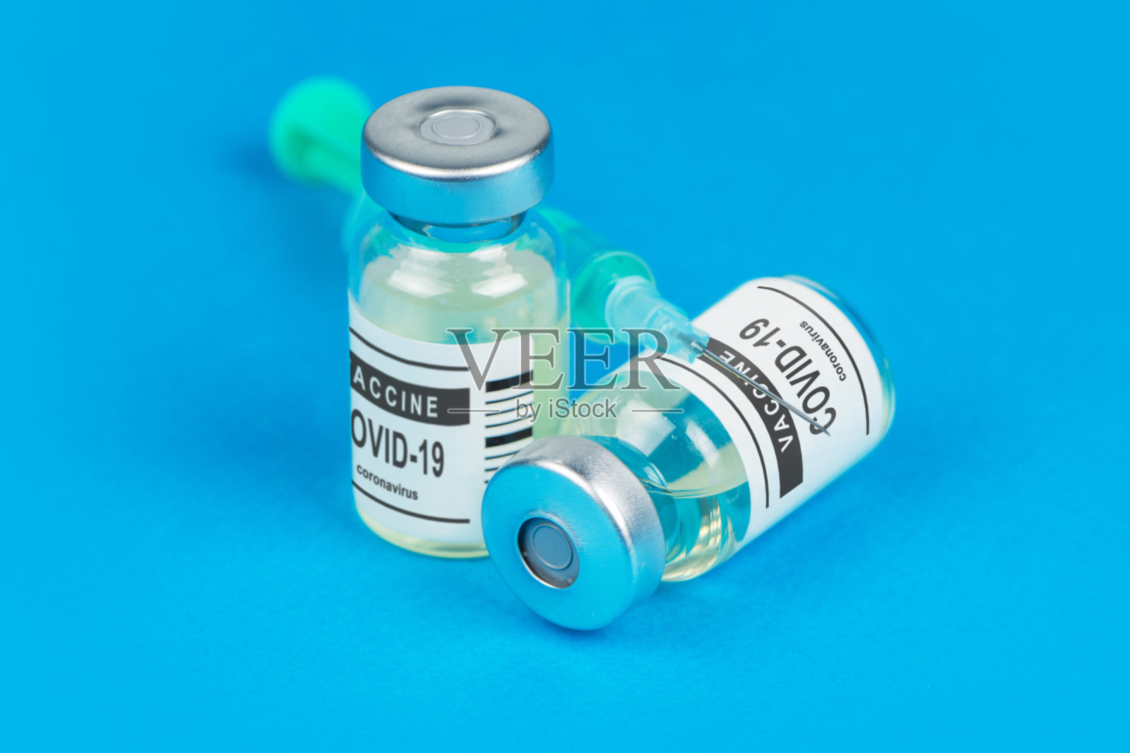 接种疫苗。COVID-19注射器和疫苗。蓝色背景下的冠状病毒照片摄影图片