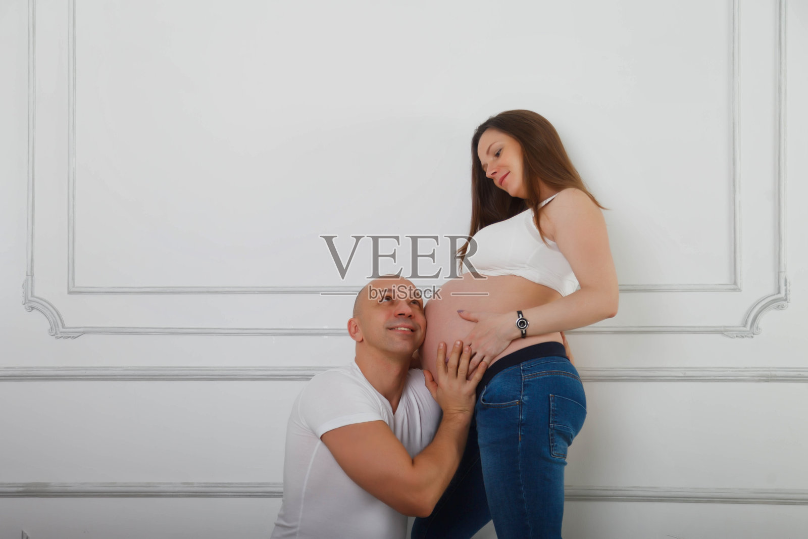 男人听年轻妻子怀双胞胎肚子照片摄影图片