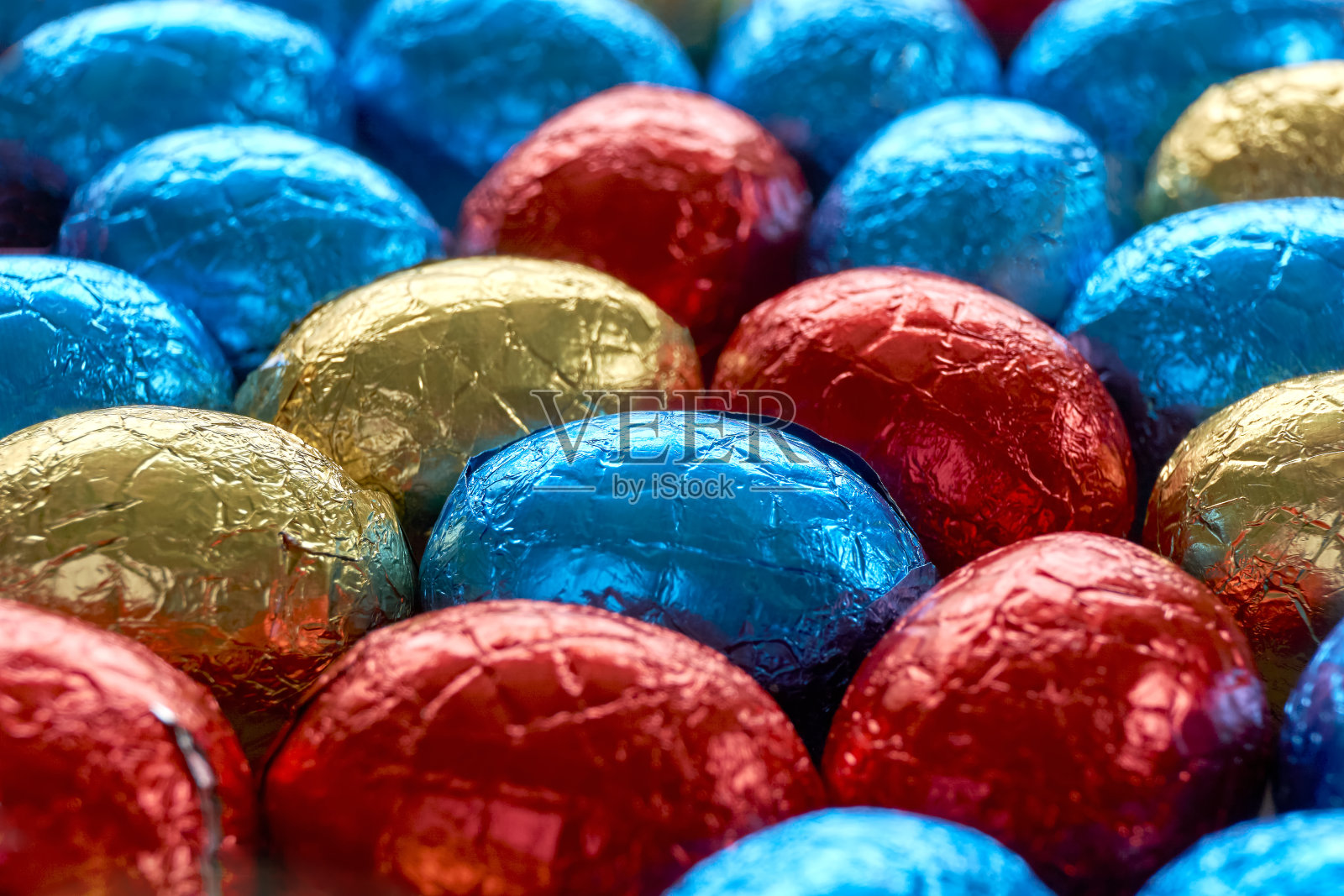 用蓝色、红色和金色的箔纸包裹的巧克力复活节彩蛋照片摄影图片