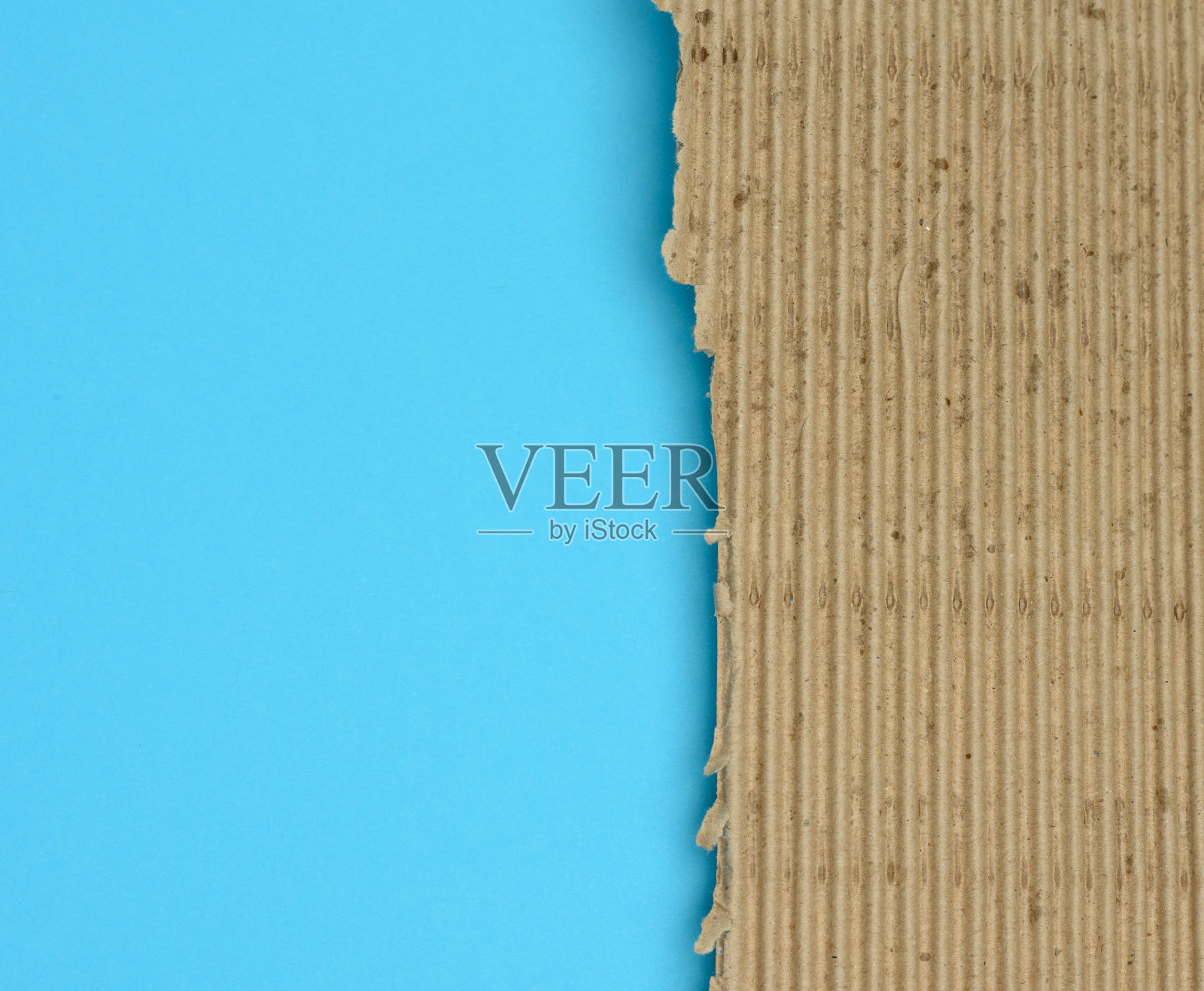 棕色的瓦楞纸板，在浅蓝色的背景上有撕裂的边缘照片摄影图片
