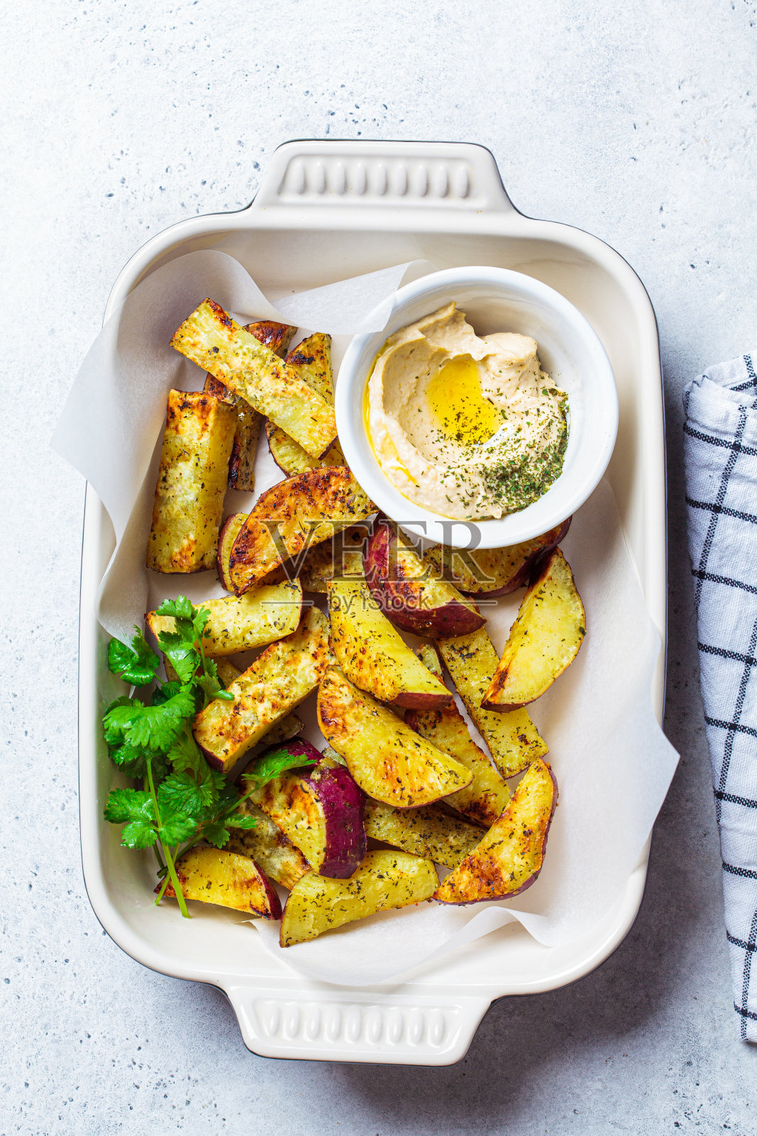 白烤箱烤甘薯配鹰嘴豆泥。素食食品的概念。照片摄影图片