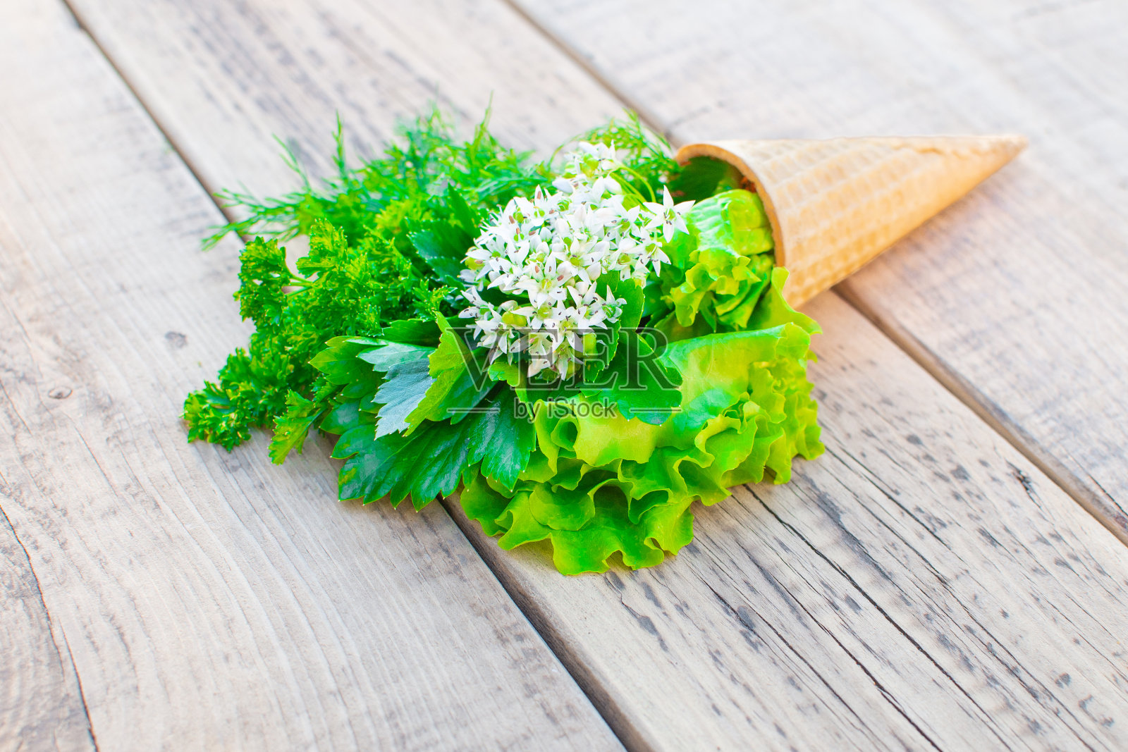 木质背景上点缀着新鲜香草的冰淇淋蛋卷。莴苣、欧芹、莳萝、蒜花。简约的夏季自然概念。春天或夏天的简约情绪。Copyscape，平放，俯视图。特写镜头。照片摄影图片