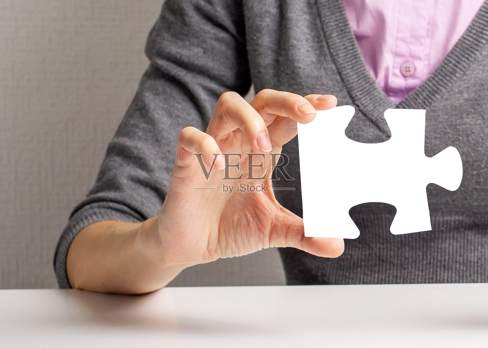 桌子边一个女人手里的拼图。找到一个解决方案照片摄影图片