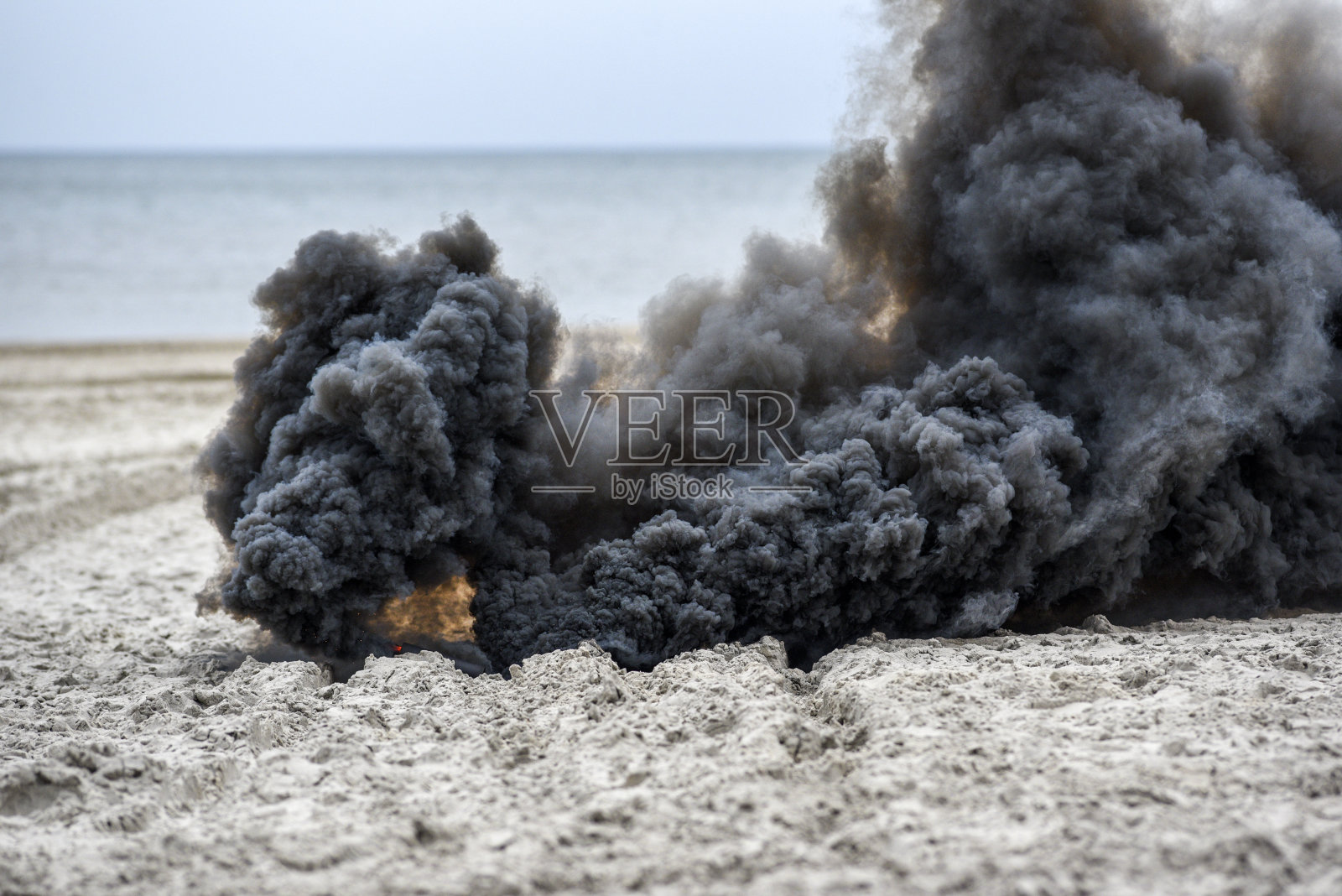 爆炸在海滩上，滚滚黑烟。照片摄影图片