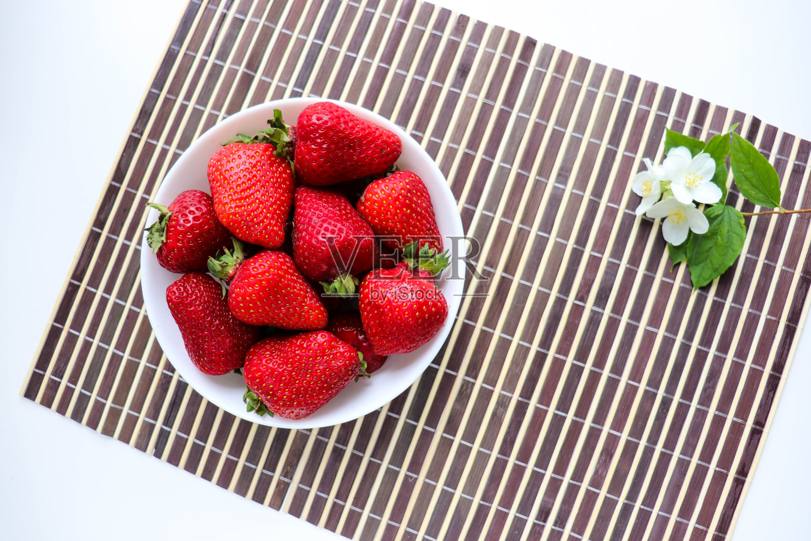 白色盘子上放着成熟的新鲜草莓和茉莉花照片摄影图片