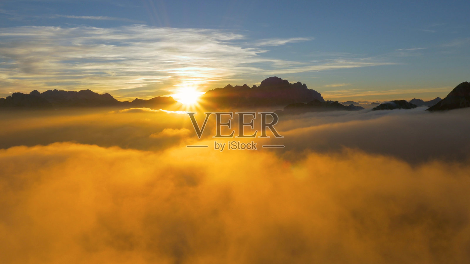 无人机:在日出时飞过法国阿尔卑斯山的云层和岩石山脊。照片摄影图片