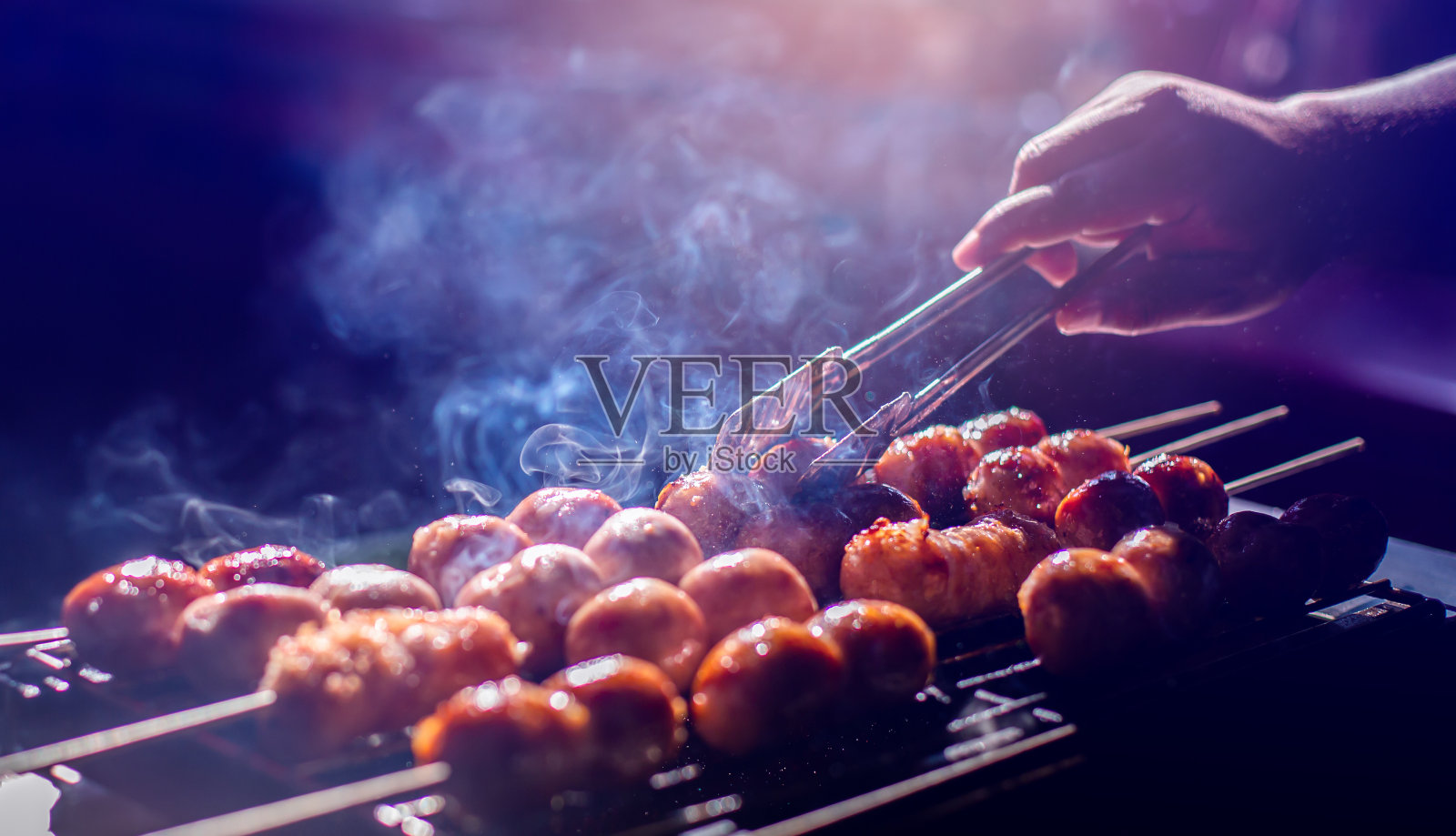 选择性地聚焦于烧烤架上的烤香肠。照片摄影图片