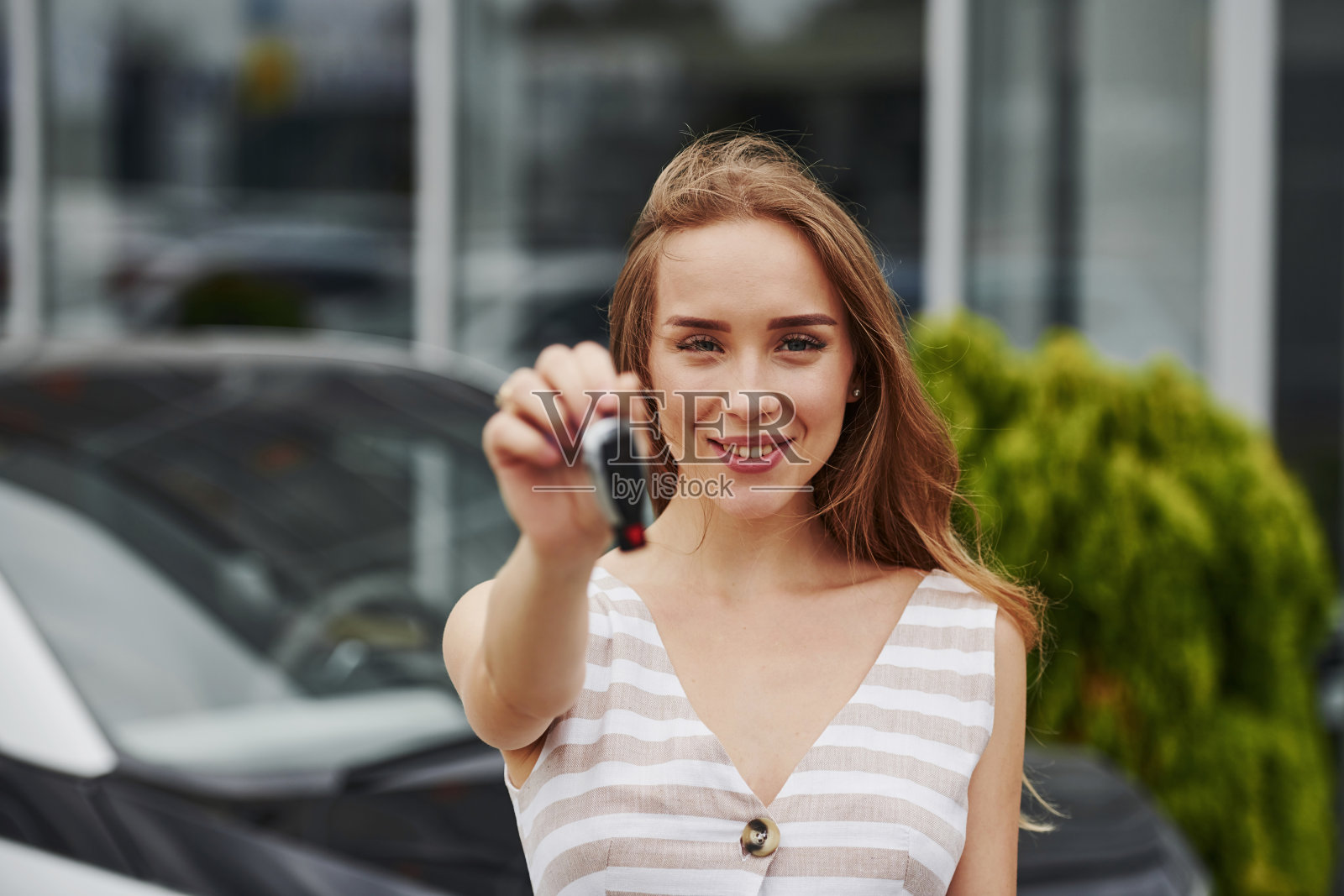 一幅欢快的金发女郎的画像，她拿着崭新的汽车钥匙照片摄影图片