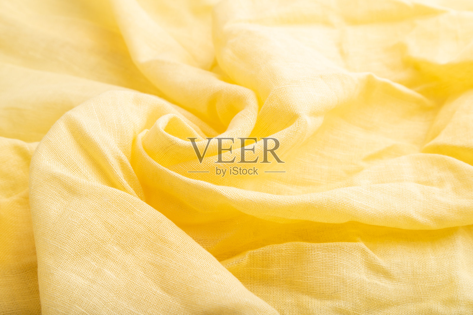 黄色亚麻织物的碎片。侧视图，天然纺织品背景和纹理。波浪概念，抽象，螺旋形。照片摄影图片