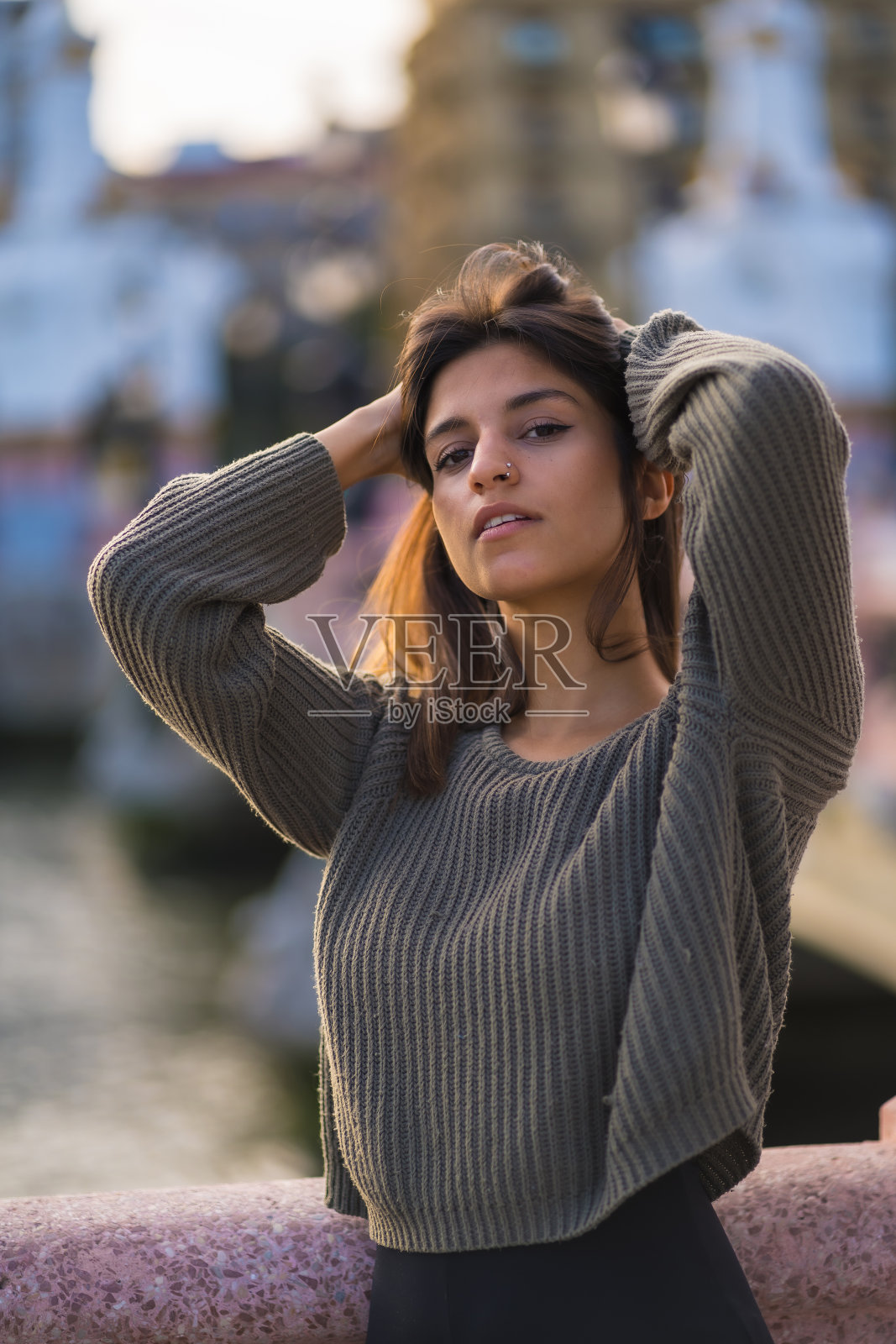 生活方式，白种人褐发穿着绿色毛衣在秋天的城市。栖息在河桥旁，街头风情照片摄影图片