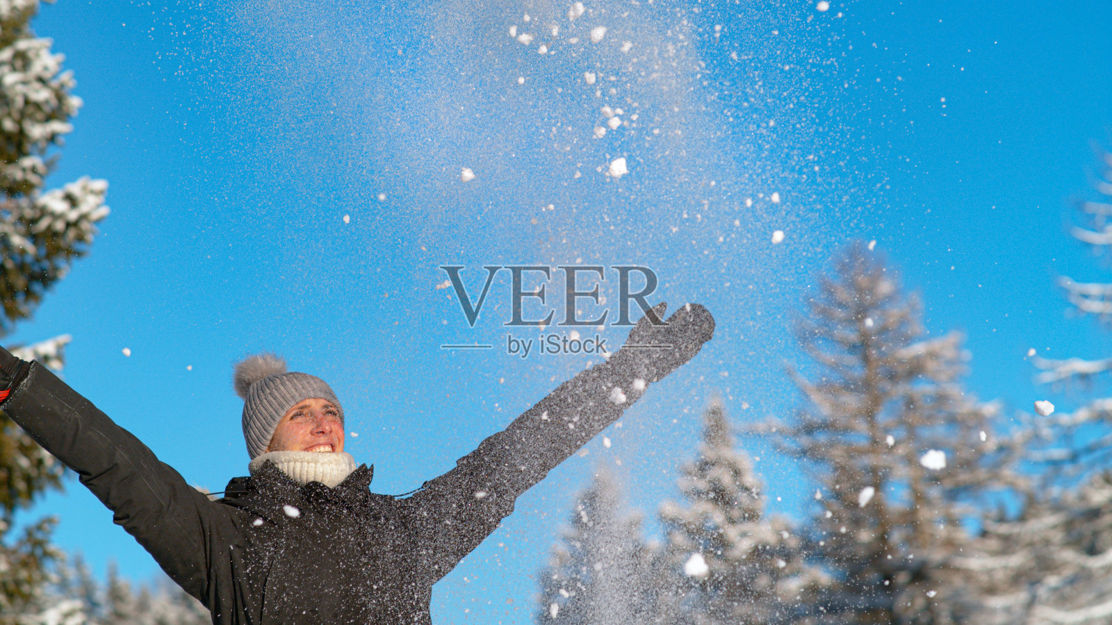 复制空间:闪闪发光的粉末雪花落在兴奋的女人的面前。照片摄影图片