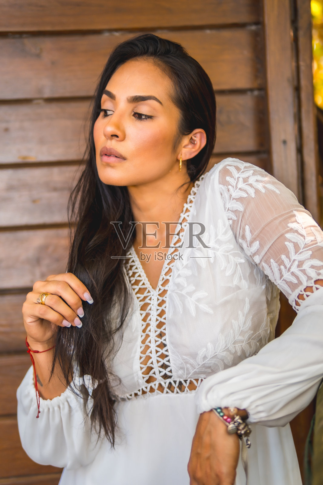 夏天的生活方式，一个年轻的拉丁黑发女子在公园里享受着白色的裙子。一个以木门为背景的漂亮女孩的肖像照片摄影图片