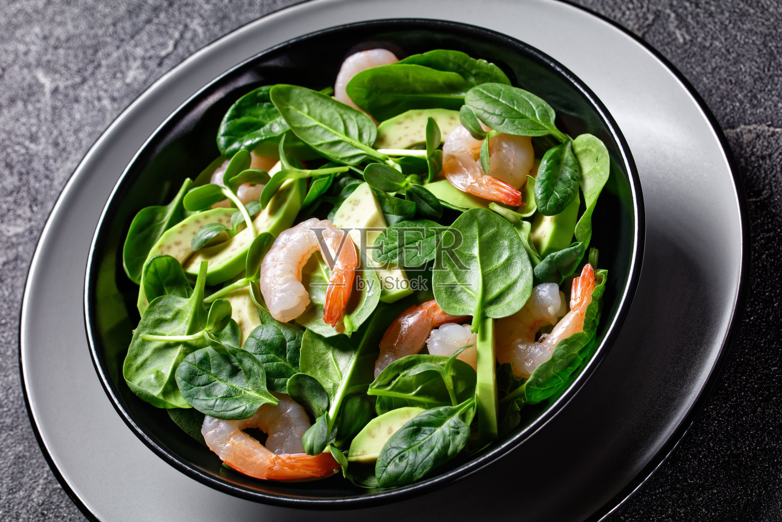 健康的鳄梨虾仁沙拉，配上嫩菠菜叶、新鲜的向日葵芽、橄榄油酱料和辣椒片，放在一个盘子里，背景用餐具，俯视图，特写照片摄影图片