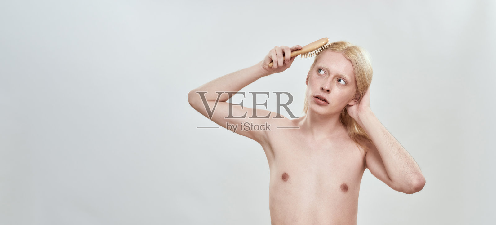 年轻的赤膊修长的白人男子梳理他的头发照片摄影图片