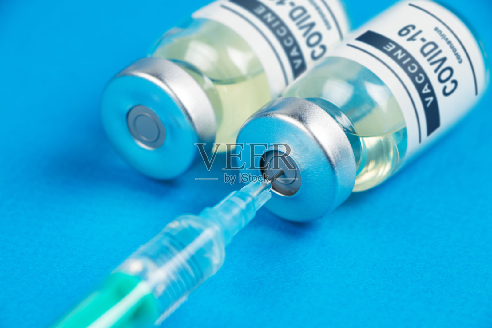 接种疫苗。COVID-19注射器和疫苗。蓝色背景下的冠状病毒照片摄影图片