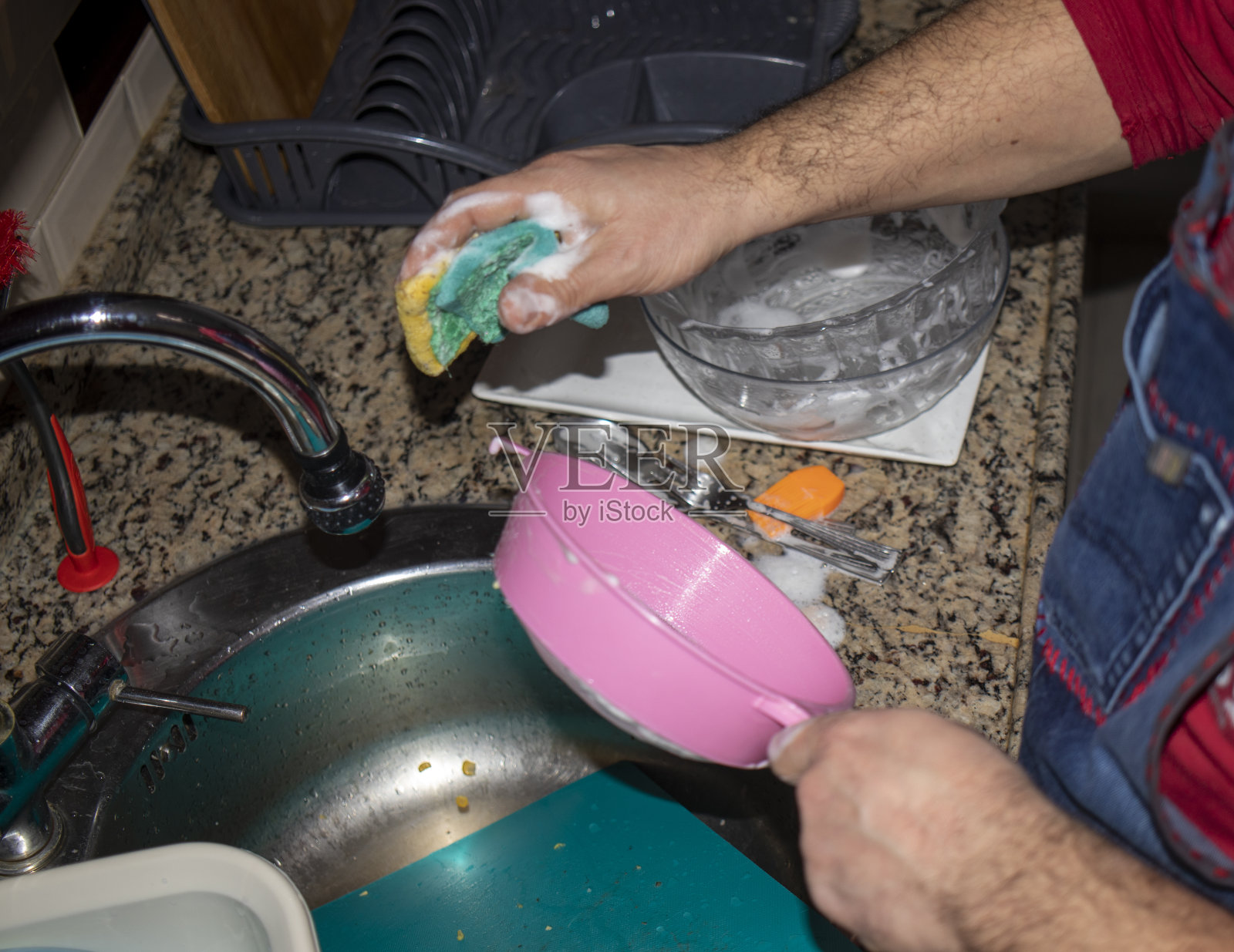 男人们在厨房的水槽里洗手和冲洗盘子。用盘子里的牛奶起泡沫，然后用水冲洗。照片摄影图片