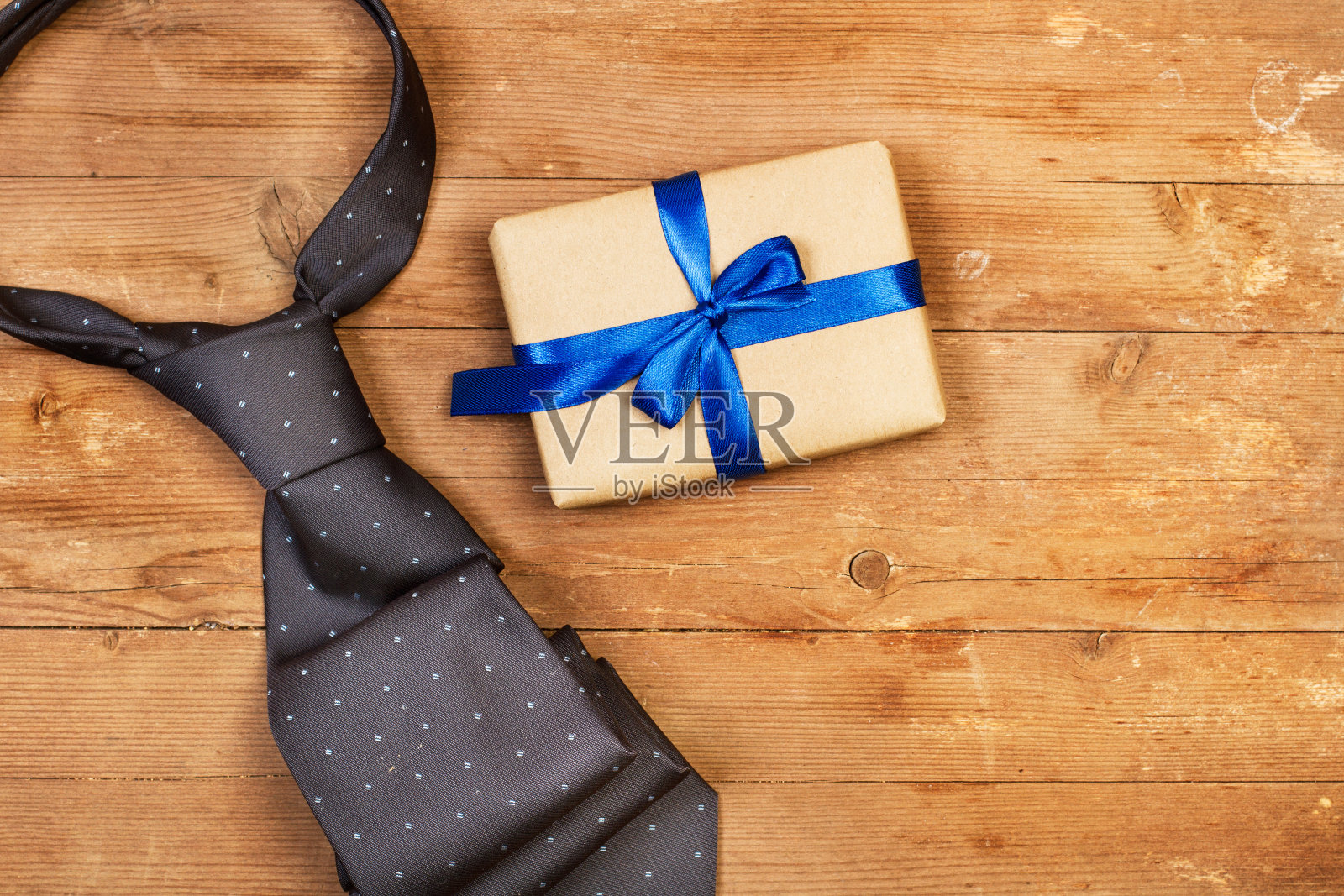 木桌上放着一条灰色领带和一份礼物照片摄影图片