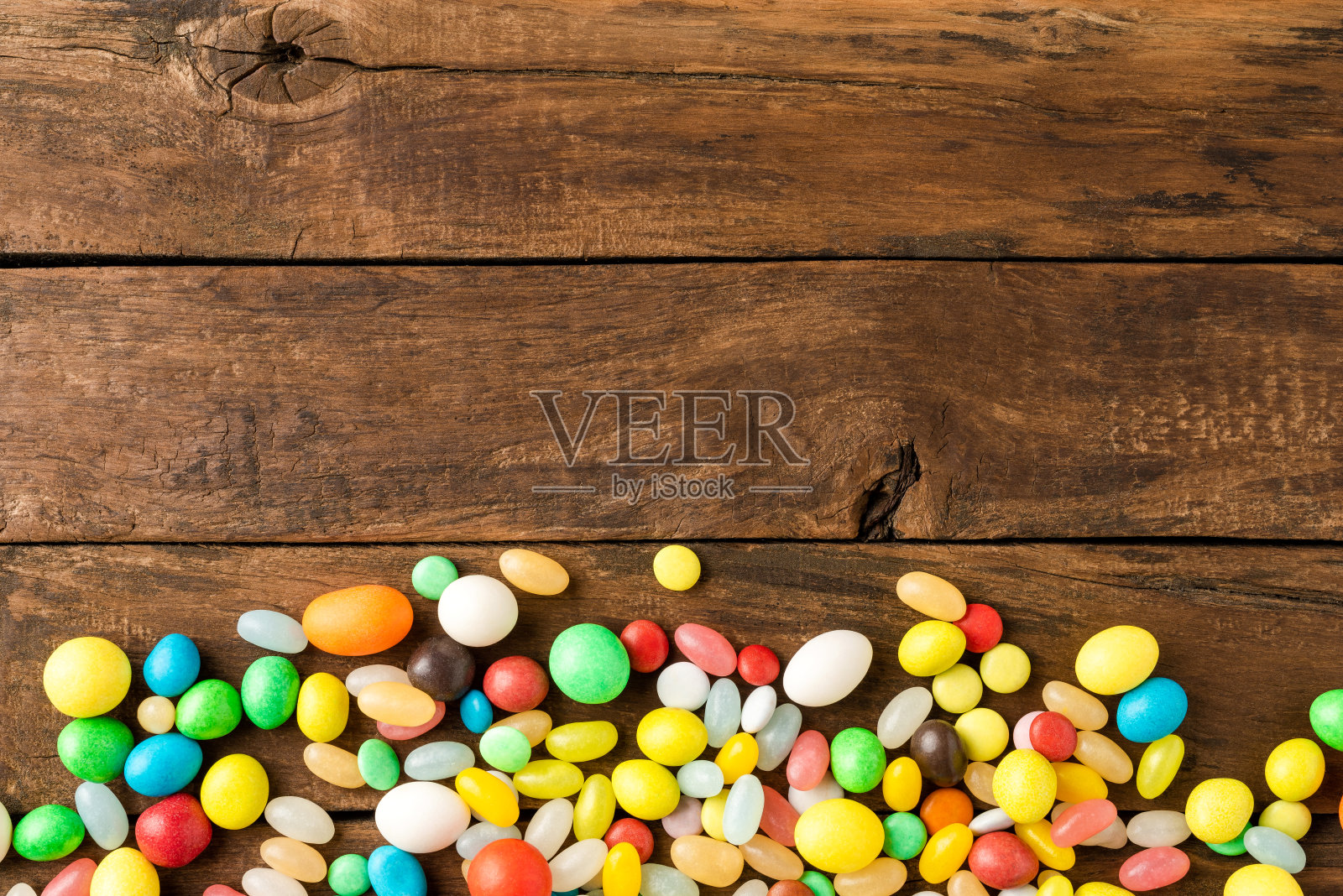 俯视不同的糖果在木制背景。不健康食品的概念照片摄影图片