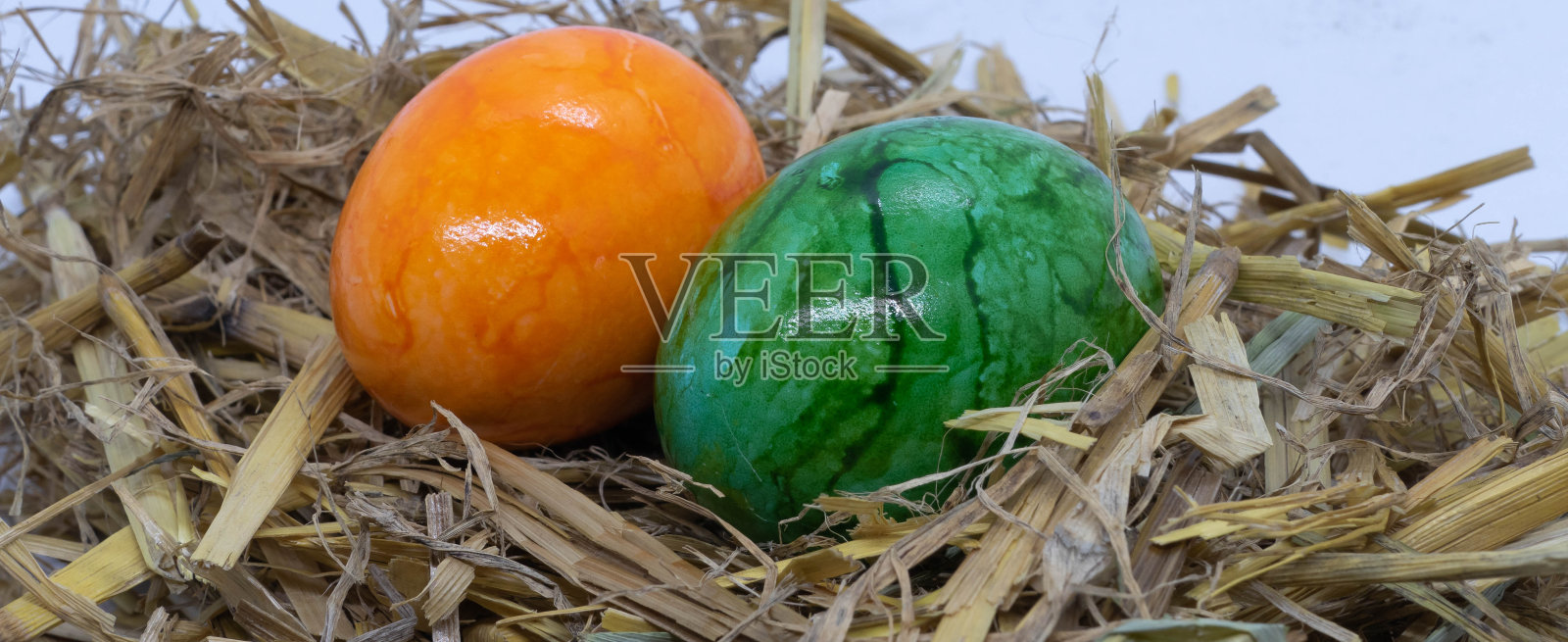 稻草中的绿色和橙色复活节彩蛋照片摄影图片