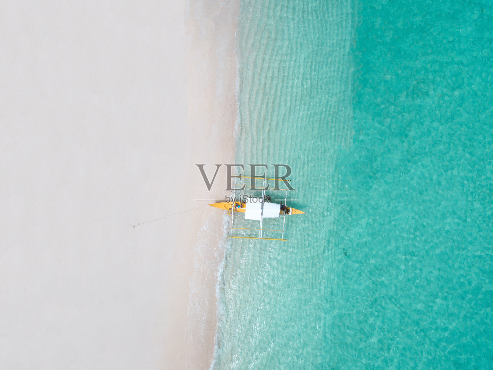 从空中俯瞰白色沙滩，一艘传统的菲律宾船只停靠在上面照片摄影图片