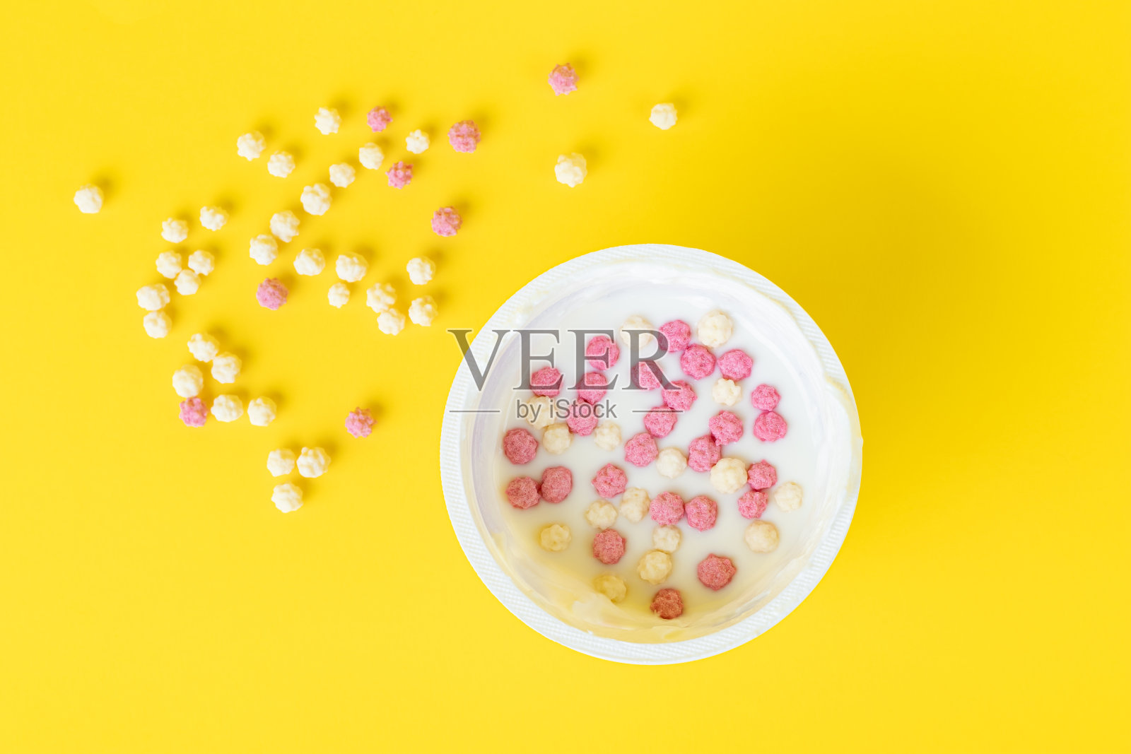 塑料杯里的酸奶，脆片，麦片。前视图。黄色背景。早上,早餐的概念。照片摄影图片