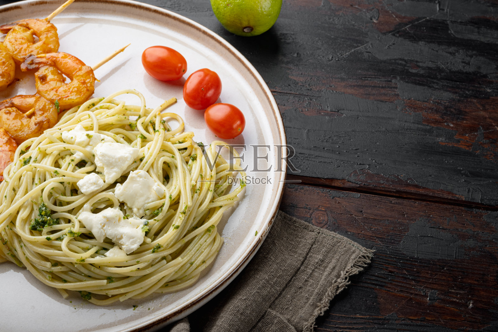 传统的意大利菜。意大利面配香蒜沙司乳清干酪和烤海鲜，放在盘子里，旧的深色木桌子背景上，有空间和文字空间照片摄影图片