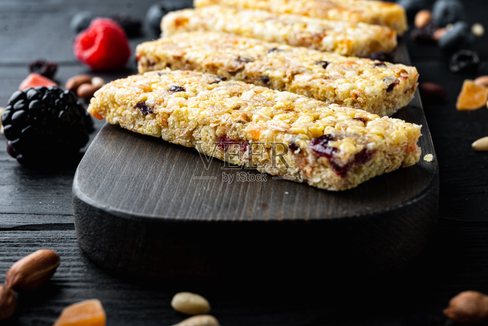 格兰诺拉麦片能量棒，坚果，种子，浆果，放在黑色的木桌上照片摄影图片