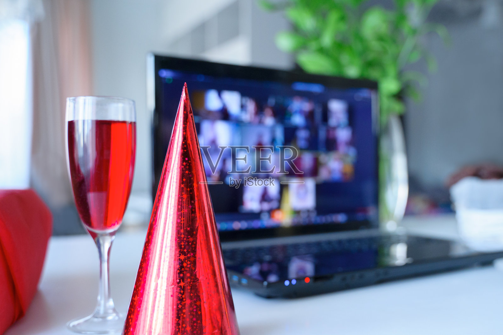 红色节日帽，一杯果汁。孩子们的虚拟生日派对。在家庆祝节日对隔离。在线会议，视频通话，笔记本电脑，动画，饼干。检疫、冠状病毒covid-19照片摄影图片