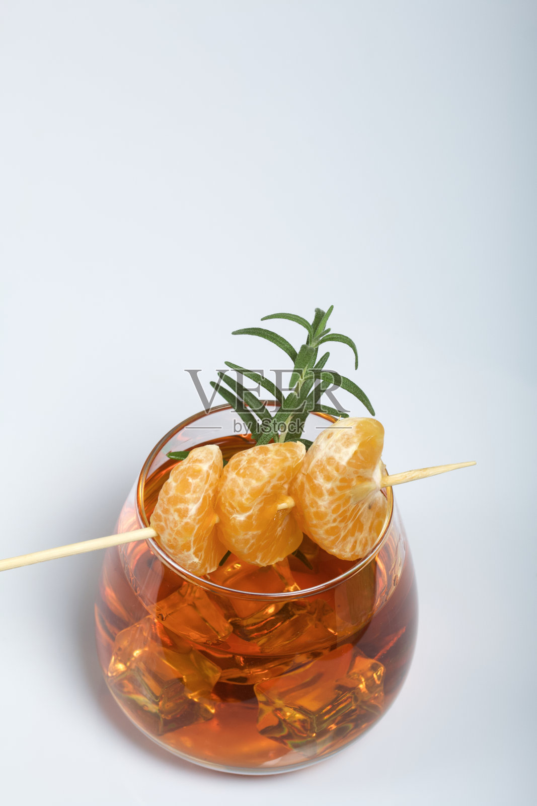 含酒精的鸡尾酒。点缀迷迭香片和橘子角。在白色的背景上。特写镜头。照片摄影图片