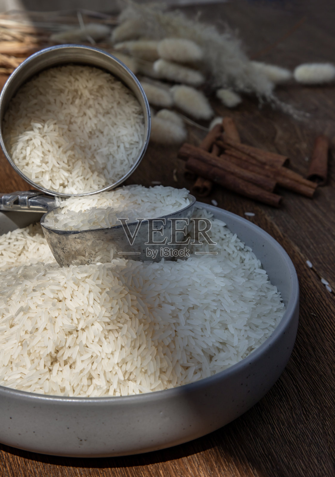 泰国茉莉花大米从旧钢罐和钢勺碗，在一个古老的乡村木制背景。照片摄影图片