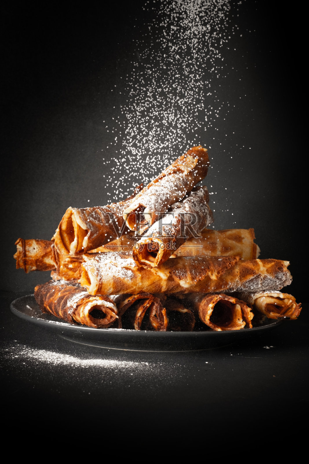 从薄面团中取出的甜饼管。美味的烤饼在深色陶瓷盘照片摄影图片