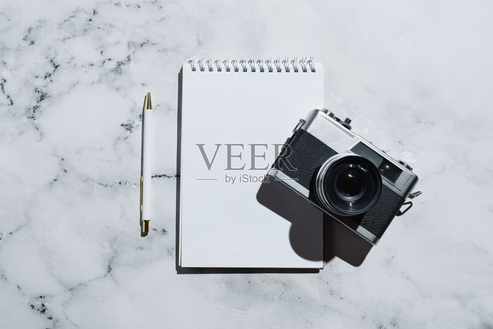 平铺的老式胶卷相机和笔记本，还有笔放在大理石上，照片摄影图片