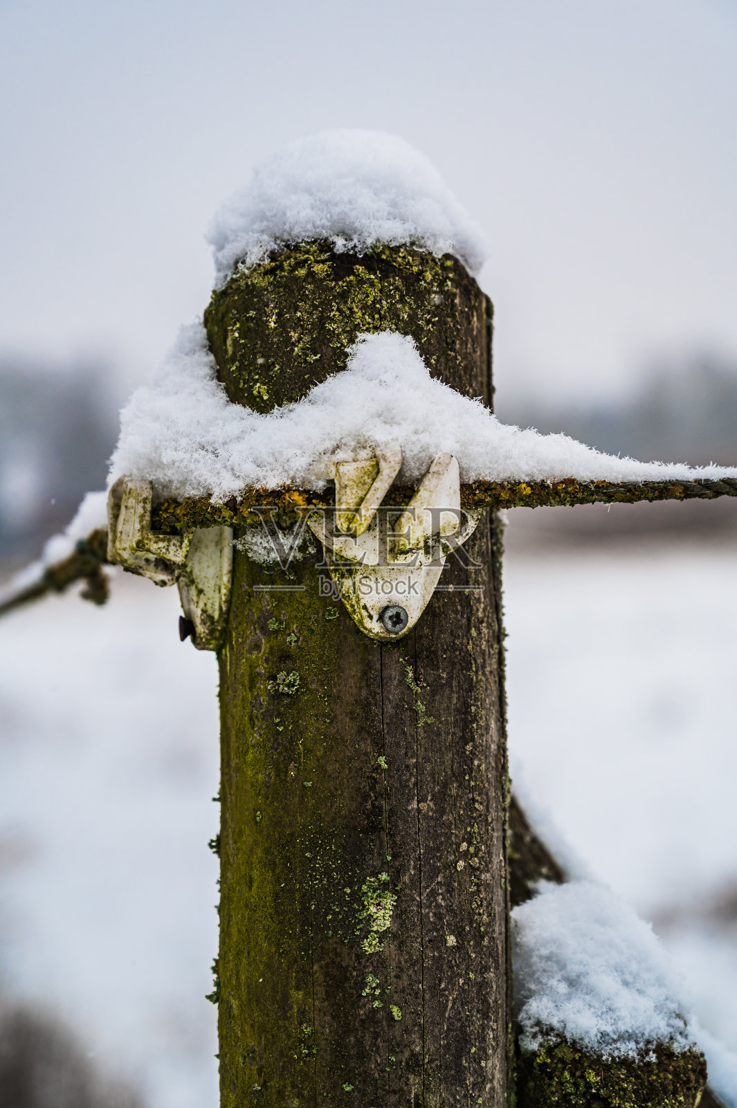 这是一幅垂直拍摄的白雪覆盖的农田木栅栏照片摄影图片