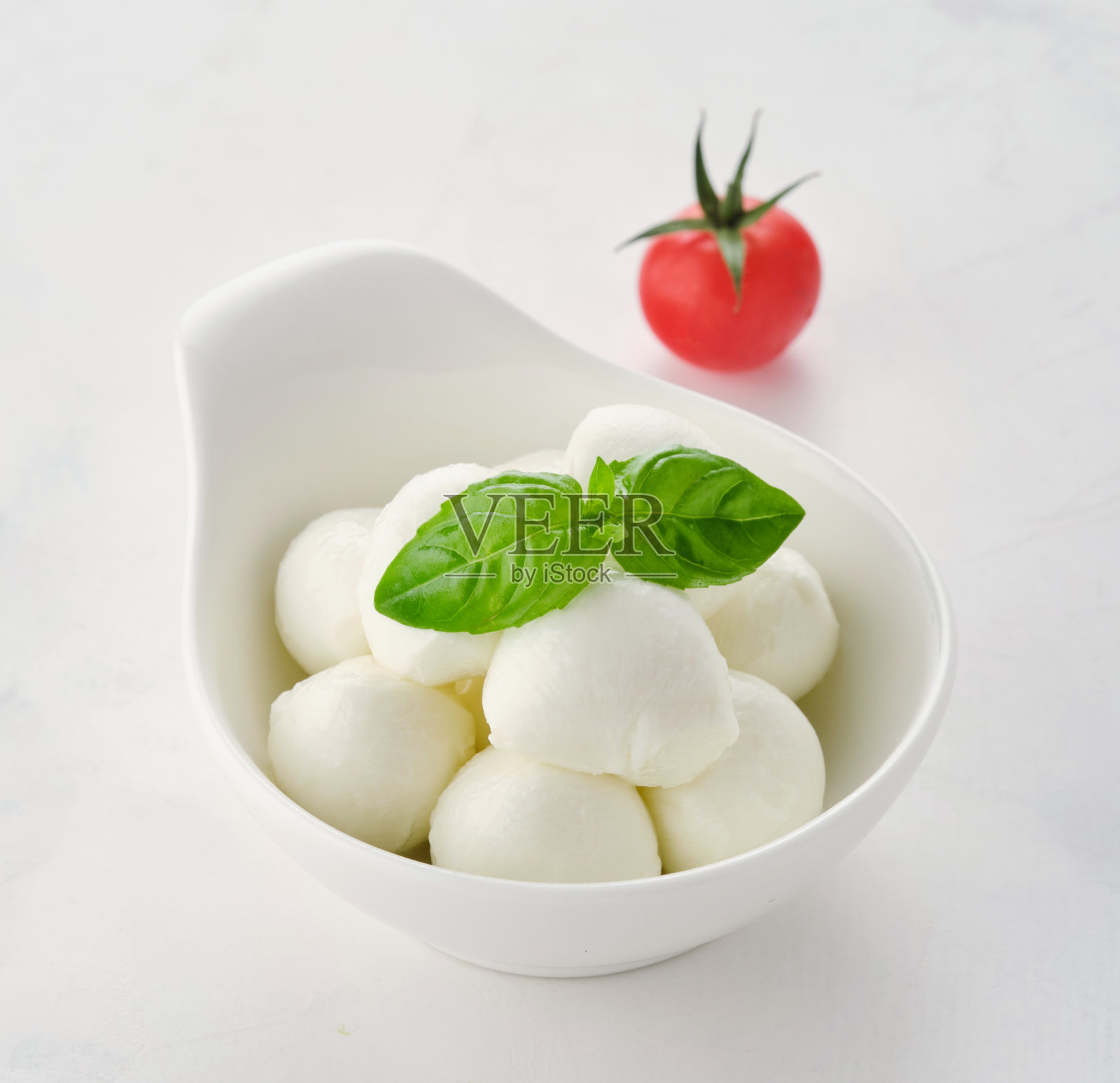 一碗小马苏里拉奶酪球加罗勒和番茄。照片摄影图片